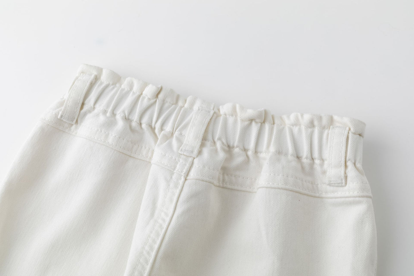 Pantalón vaquero largo de bebé niña, de cinco bolsillos, y cintura alta de goma. Prenda color blanco.