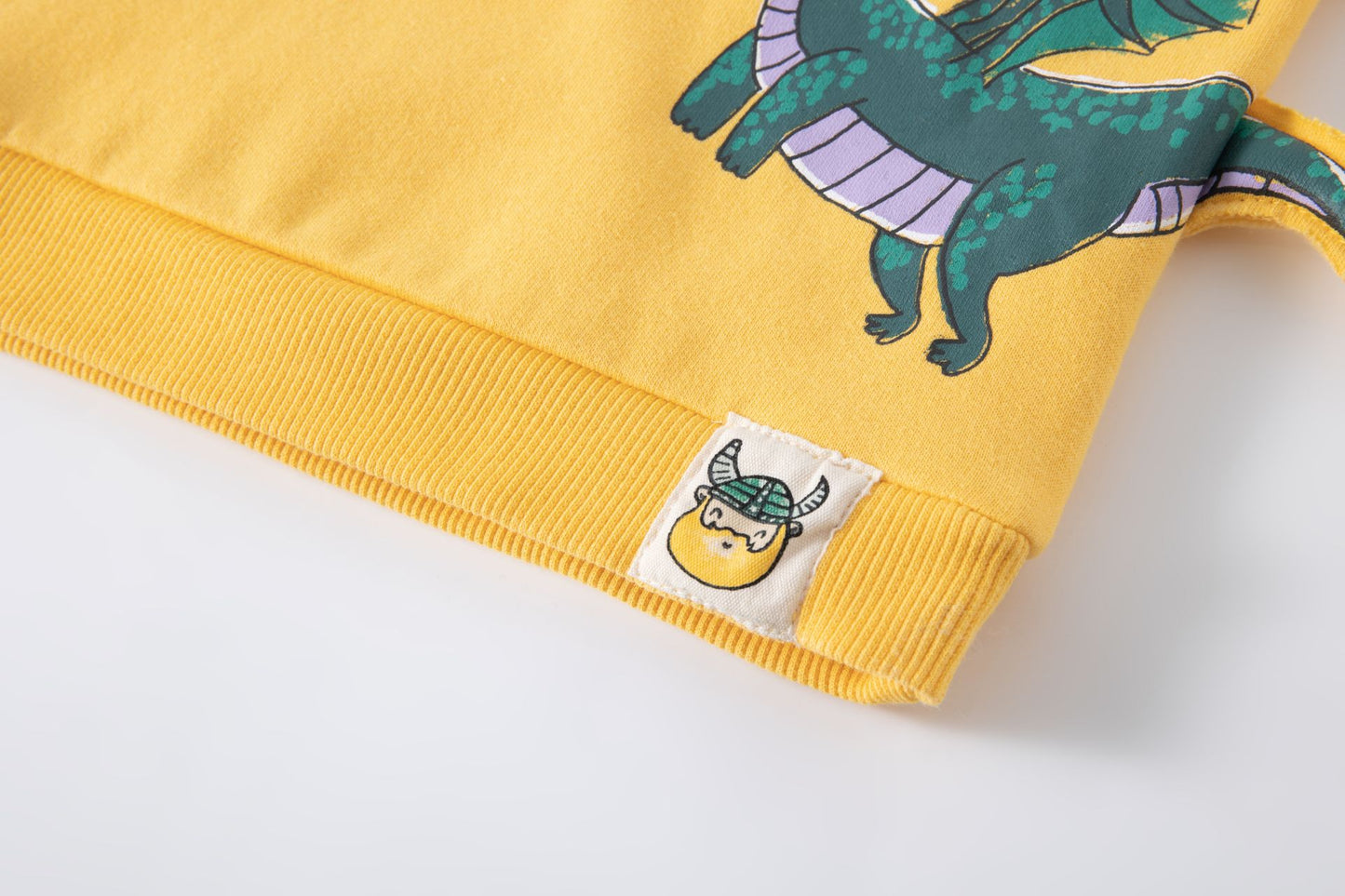 Sudadera de bebe niño, cuello caja y hombros caídos. Felpa perchada. Gráfico imitando bolsillo frontal y de dragón estampado al agua, con cola en 3D. Etiqueta decorativa. Abertura de corchetes en hombro.